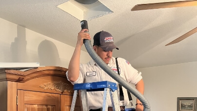 A tech vacuming out an air duct.